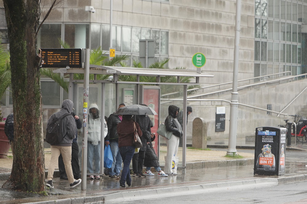A rainy, stormy day in Dublin. Peaple waiting for the bus at a bus stop.