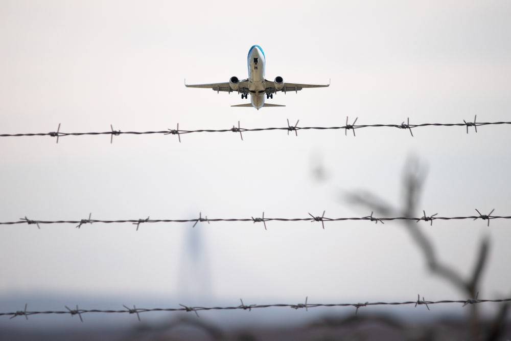Passenger plane flying by barbed wire.
