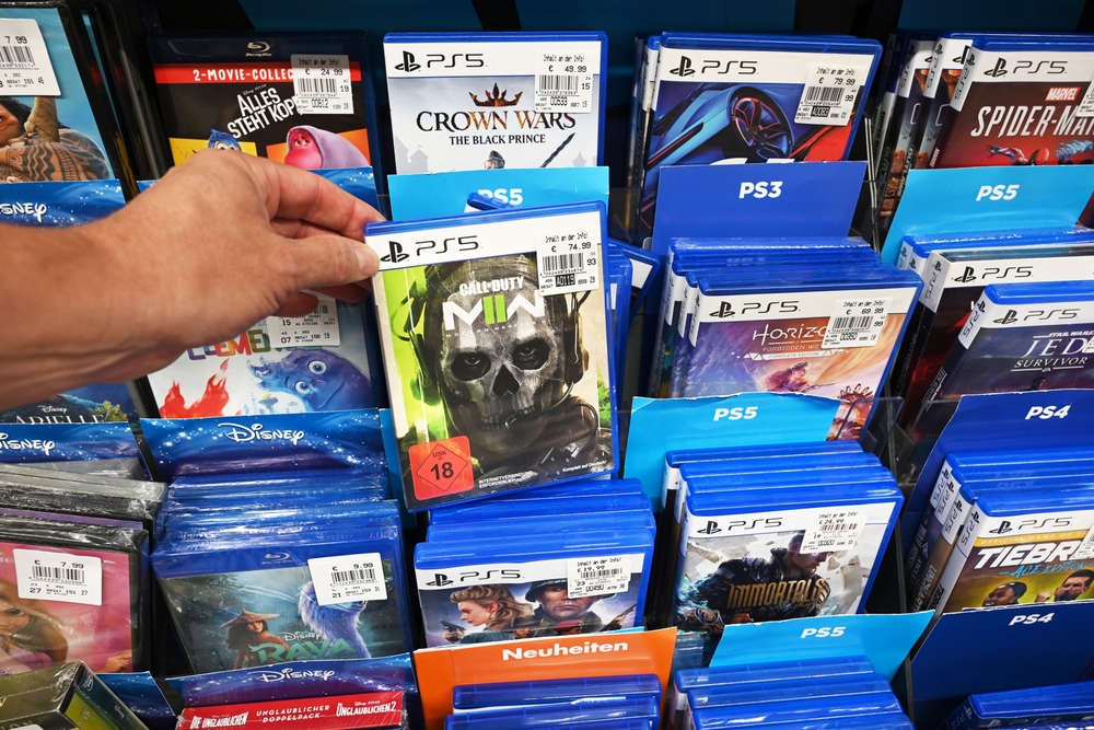 PlayStation Will Scrap Physical Game Discs For Digital Downloads 3 PlayStation disc games in shop aisle. Defotoberg, Shutterstock