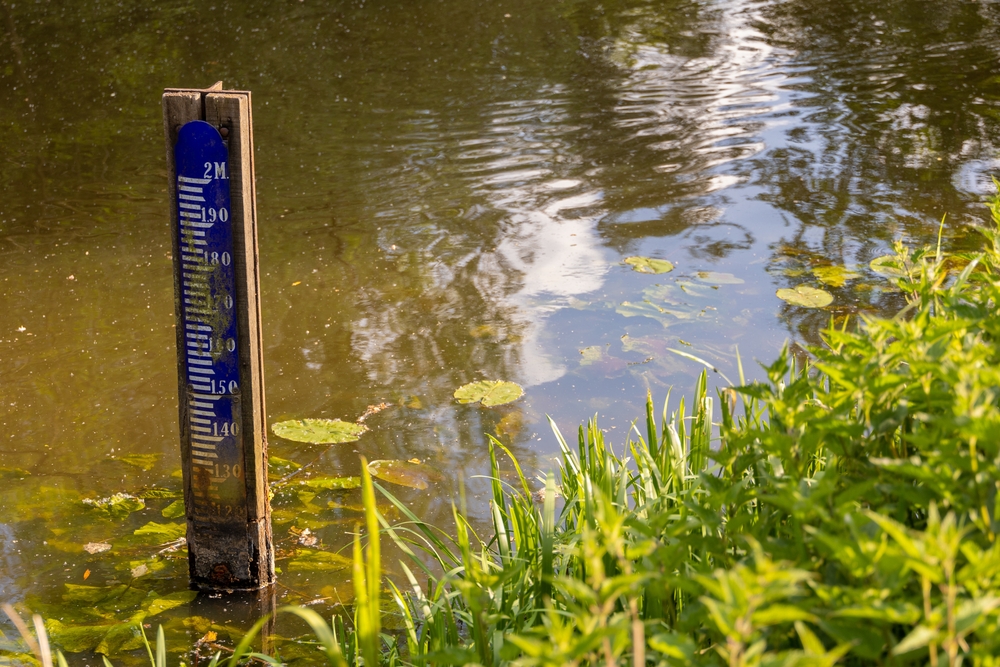 Water level depth meter, gauge or staff. Extreme low water level in river. Global warming. Shortage, scarcity or lack of water or rain due to hot temperatures. Climate change crisis